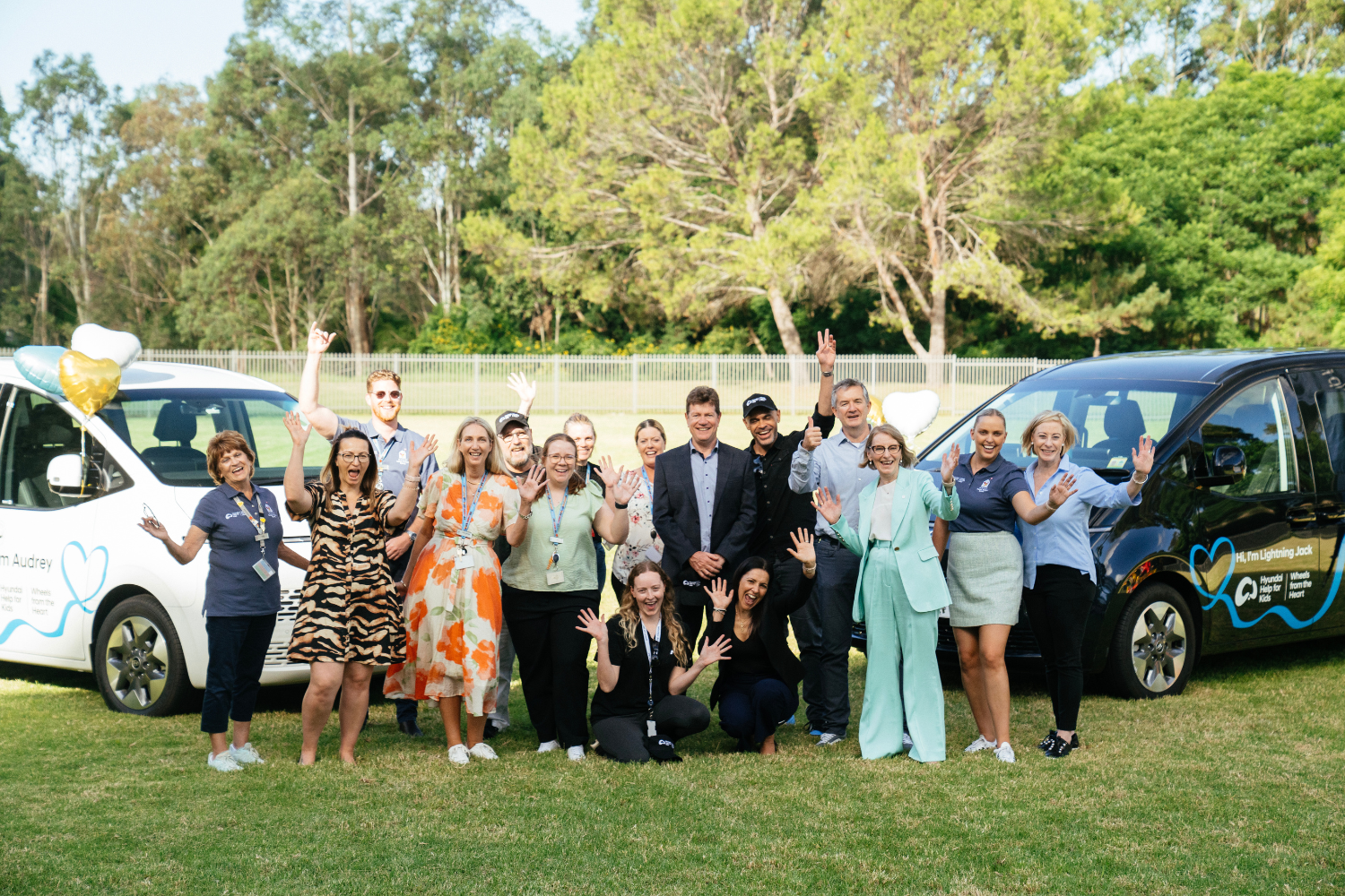 Group of people with arms up celebrating in front of two Hyundai vans