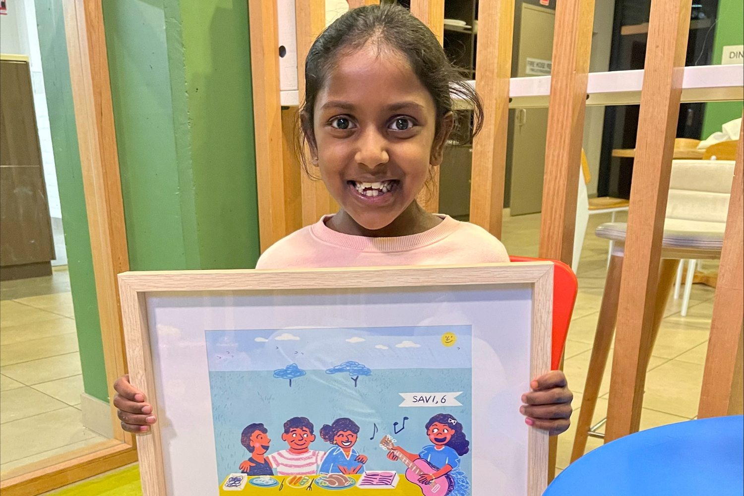 Savi holding an artwork from the Steggles Charity Chook of her family